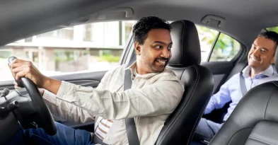 A smiling driver and passenger inside a comfortable sedan, representing rent a car with driver in Lahore service.